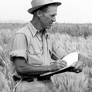 Norman Borlaug in field with notebook